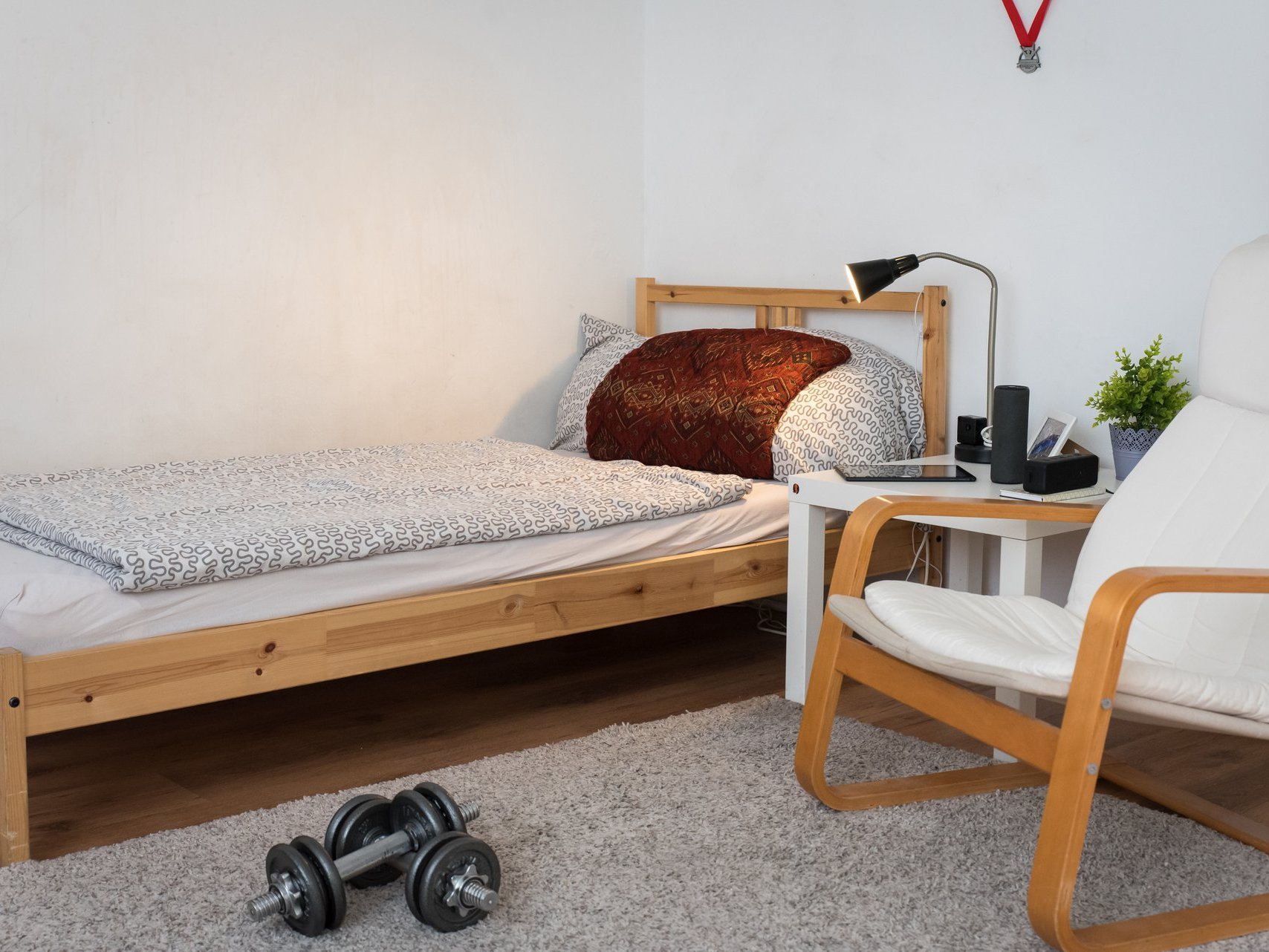 Zimmer mit Bett - im Vordergrund liegen Hantel-Gewichte und an der Wand hängen zwei Sportmedaillen 