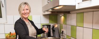 Frau beim Kochen lächelt in die Kamera