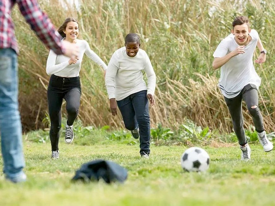 Jugendliche spielen um den Ball kämpfend Fußball