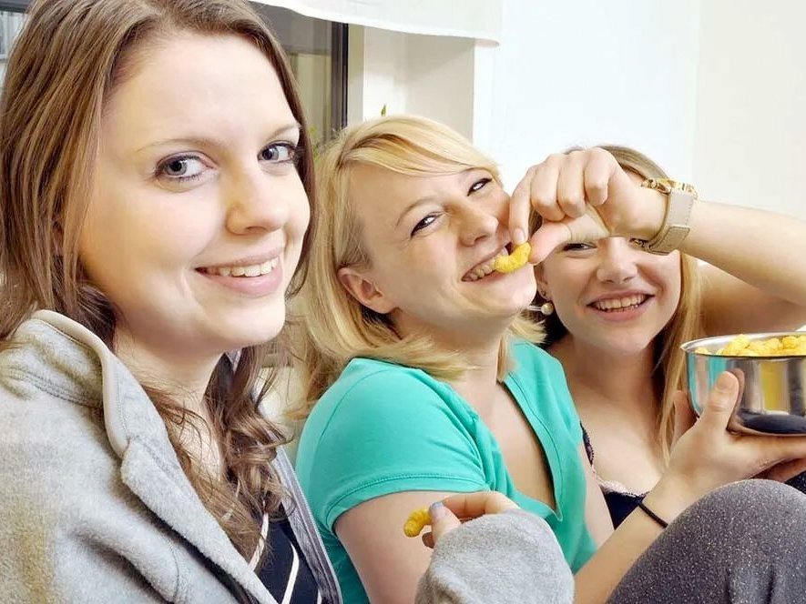 Junge Frauen beim gemeinsamen Ednussflips essen haben Spaß