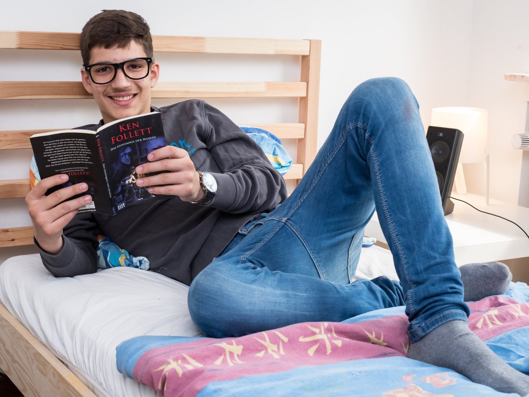 Jugendlicher beim Lesen eines Buchs auf dem Bett